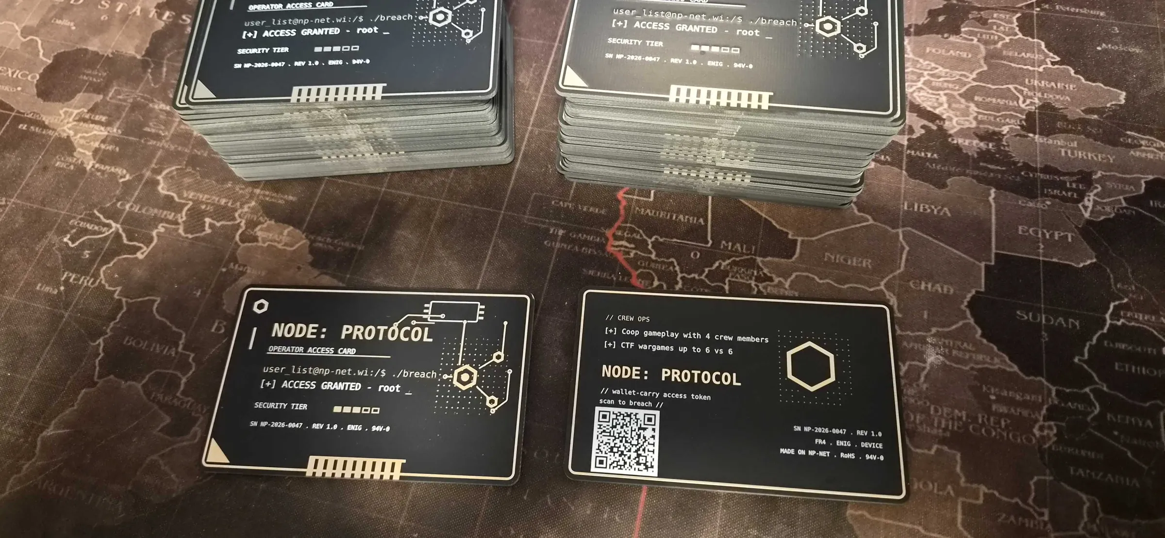 Stapel von NODE: PROTOCOL Operator Access Cards, eine Vorder- und eine Rückseite auf einer Weltkarte ausgelegt